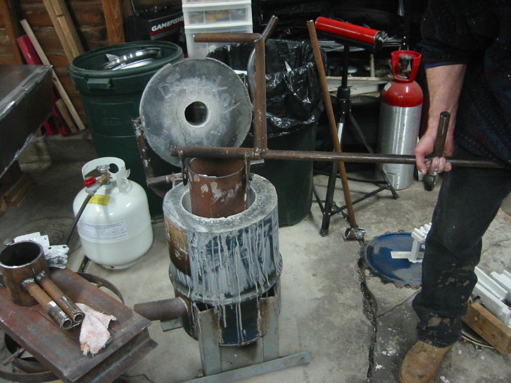 Hooks on a swivel latch onto ears on the crucible to lift it from the foundry.