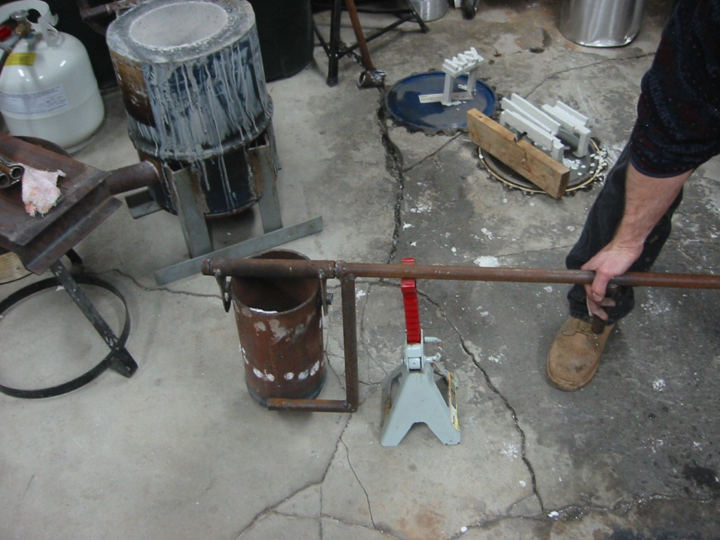 Tilting arm that is welded to the handle is rotated down to tilt the crucible for pouring.